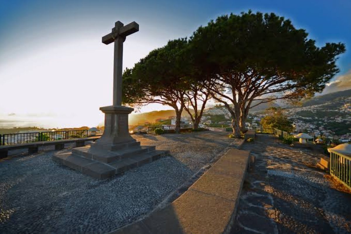 Pico dos Barcelos viewpoint with a stone cross and pine trees overlooking Funchal, Madeira